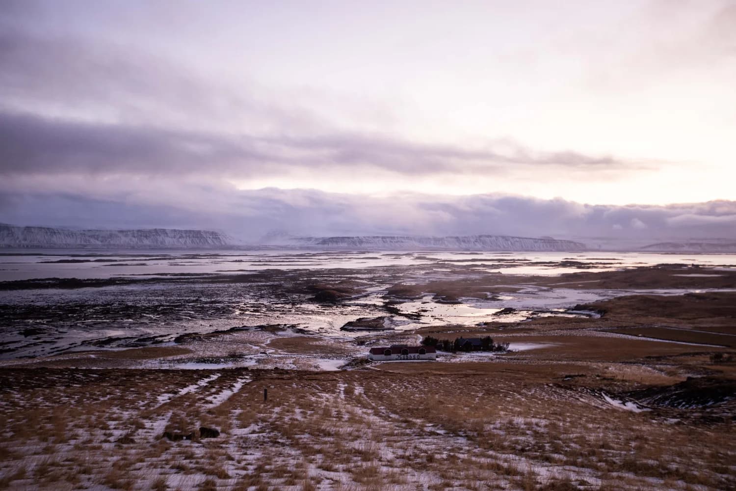 Wide coastal plain at dusk beneath layered clouds