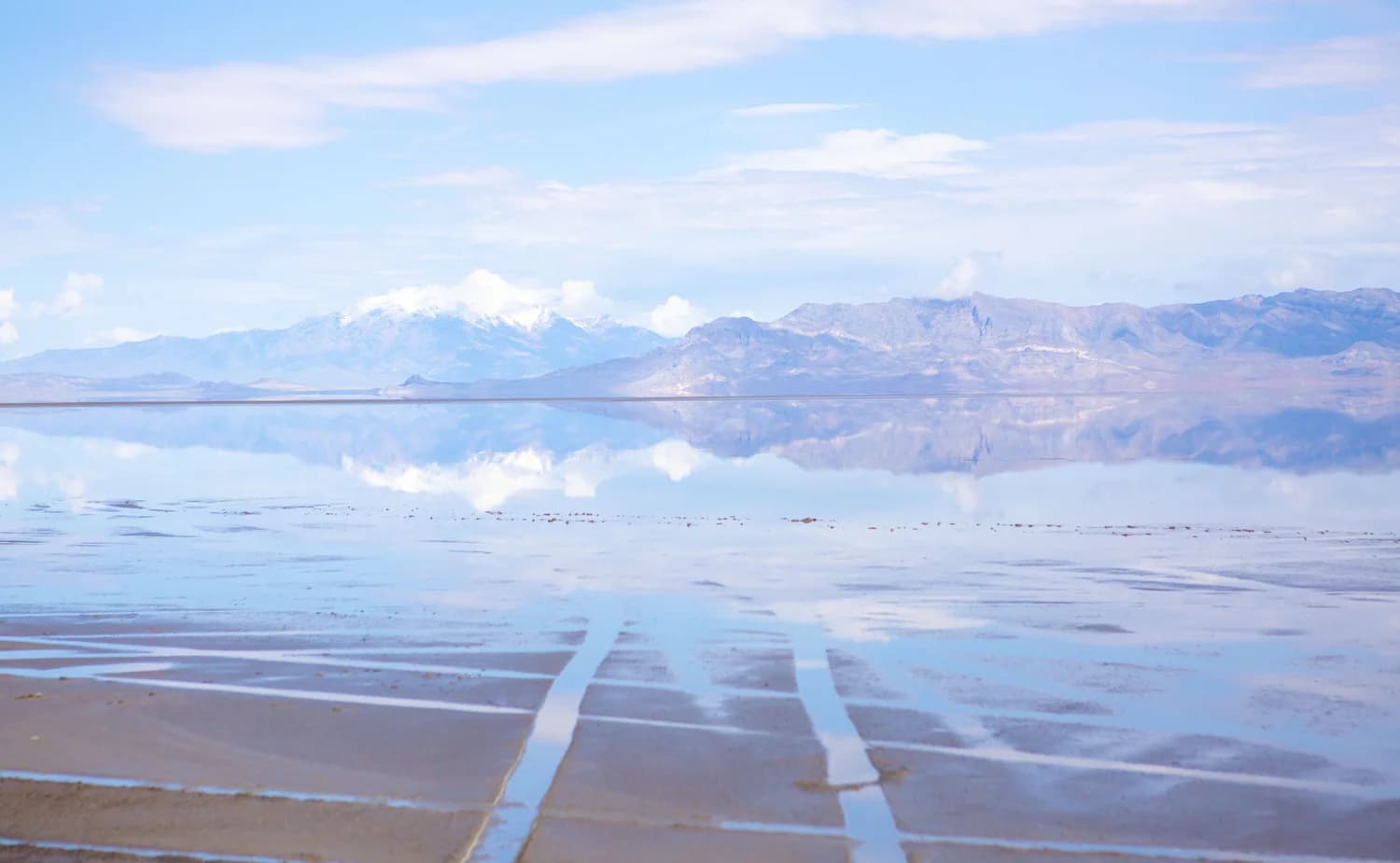 Distant mountains mirrored in a thin sheet of water across salt flats
