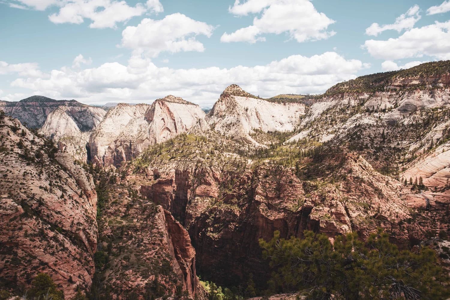 Pale sandstone peaks and green canyon ridges under scattered clouds